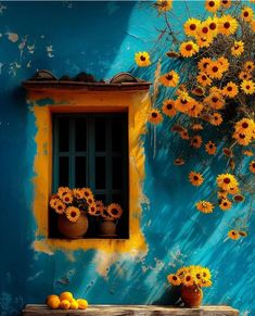 sunflowers are growing on the side of a blue wall with yellow flowers in pots