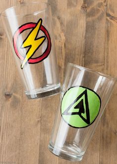 two shot glasses with stickers on them sitting next to each other in front of a wooden table