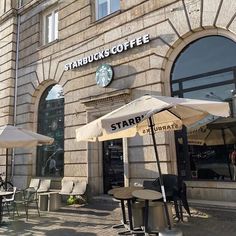 there are many tables and umbrellas outside the starbucks