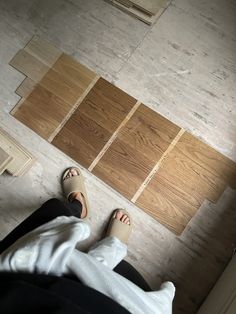 a person sitting on the floor with their feet up in front of some wood planks