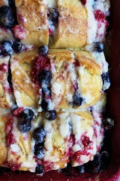 blueberry bread rolls in a red casserole dish with fresh berries on top