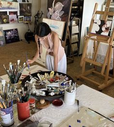 a woman painting in an art studio with lots of easels and paintbrushes