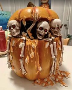 three skeletons sitting in a pumpkin decorated with orange and white icing on top of a table