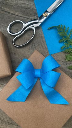 a pair of scissors sitting on top of a piece of paper next to a present box