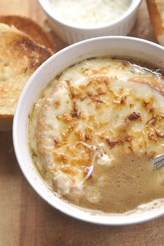 there is a bowl of soup with bread on the side