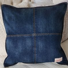 a blue denim pillow sitting on top of a bed