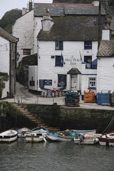 there are many small boats docked in the water near this white building with blue windows