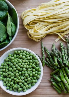 asparagus, pasta and green beans on a wooden table with two bowls of noodles