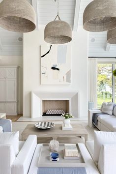 a living room filled with white couches and chairs next to a fire place in a fireplace