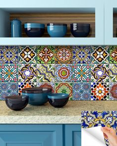 a kitchen with blue cabinets and colorful tile backsplashes on the counter top