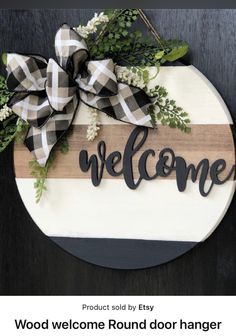 a welcome round door hanger with the word welcome on it in black and white