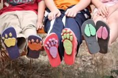 four children sitting on a bench with their feet up