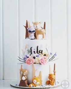 a three tiered cake decorated with animals and flowers