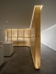 an empty room with white counter tops and gold colored panels on the wall behind it