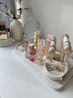 a white counter topped with lots of different types of cosmetics and perfume bottles on top of it