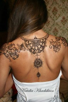 the back of a woman's neck with henna tattoos on her left shoulder