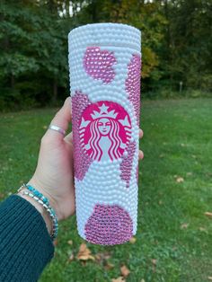 a hand holding up a starbucks cup decorated with beads and hearts in the shape of a woman's face