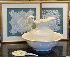 a white vase sitting on top of a counter next to a framed piece of art