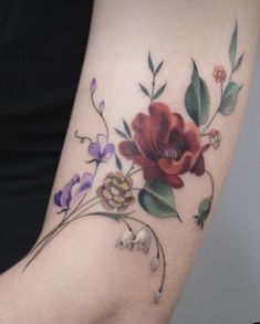 a woman's arm with flowers and leaves painted on the back of her arm