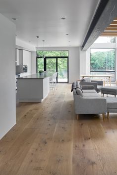 a living room filled with furniture next to a kitchen and an open floor plan on top of a hard wood floor