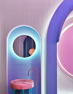 a bathroom with pink and blue walls, an oval mirror and a round sink