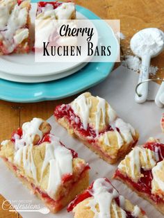 cherry kuchen bars with white icing on a plate next to other desserts