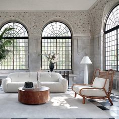 a living room filled with white furniture and large windowed windows over the top of them