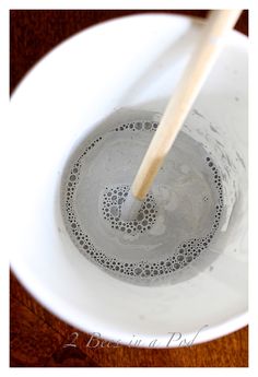 a wooden stick sticking out of the top of a bowl filled with water and liquid