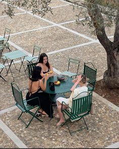 three women sitting at a table outside eating