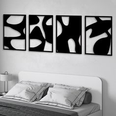 three black and white paintings hanging on the wall above a bed in a room with two lamps