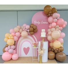 a pink and gold baby shower party with balloons in the shape of a house, heart shaped cake