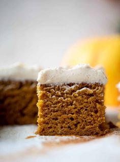 a close up of a piece of cake with frosting on it and an orange in the background