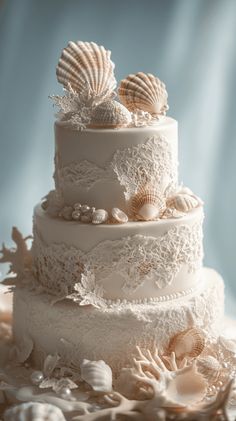 a three tiered wedding cake with seashells on top