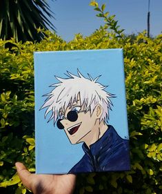 a person holding up a painting of an anime character in front of bushes and trees