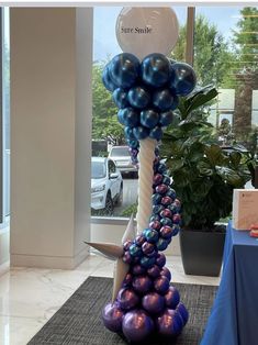 the balloon column is decorated with blue, purple and silver balloons in front of a window