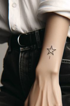 a woman's arm with a star tattoo on her left wrist and black jeans