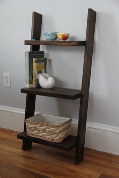 a wooden shelf with two shelves and a basket on it next to a white wall