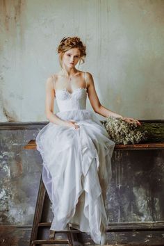 a woman in a white dress is sitting on a stepladder holding a bouquet