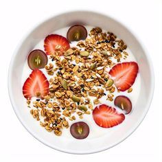 yogurt with granola, fruit and nuts in a bowl on a white background