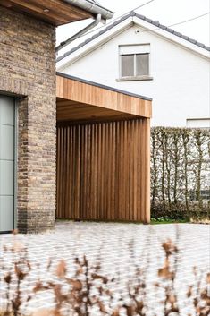 an open garage door in front of a brick building with wooden slats on the side