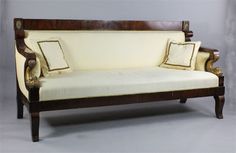 an old fashioned wooden couch with two pillows on it's back and armrests