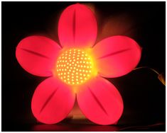 a flower shaped light is lit up in the dark with its petals turned yellow and red