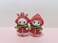 two small stuffed animals wearing red outfits