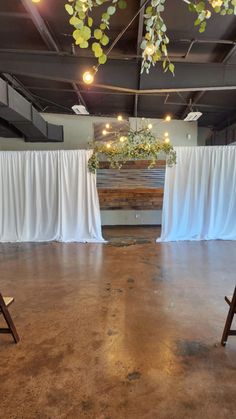 an empty room with white drapes on the ceiling and chairs in front of it