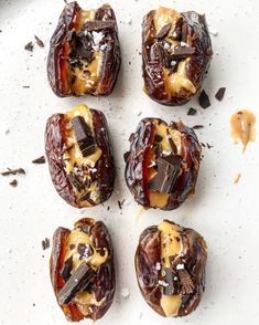 four chocolate covered donuts sitting on top of a white plate with caramel sauce