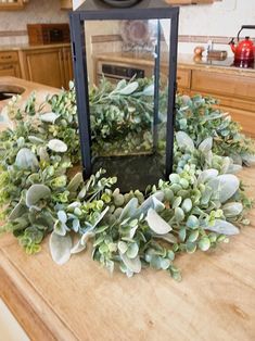 a lantern is sitting on top of a counter with some greenery in front of it