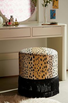 a leopard print stool sits in front of a vanity with a mirror and vase on it