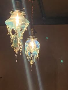 two light fixtures hanging from the ceiling in a room with lights on them and one is lit up