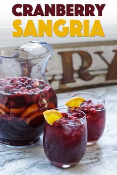 two glasses filled with fruit and ice on a table next to a pitcher of water