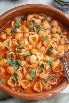 a bowl filled with pasta and garnished with parsley on the side next to a spoon